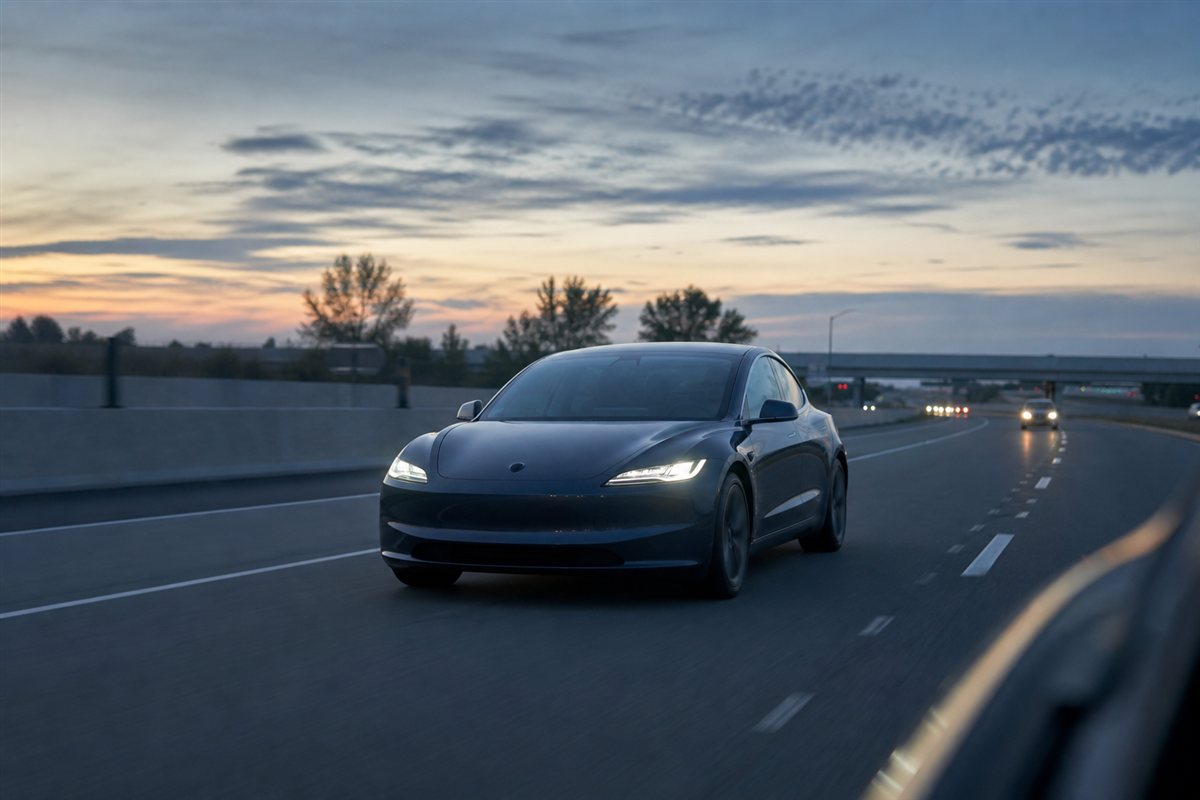 Electric sedan traveling within marked highway lanes at dusk